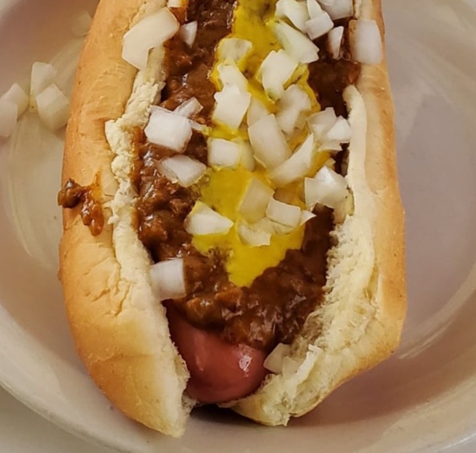 chili dog in bun with chilli, cheese and onions